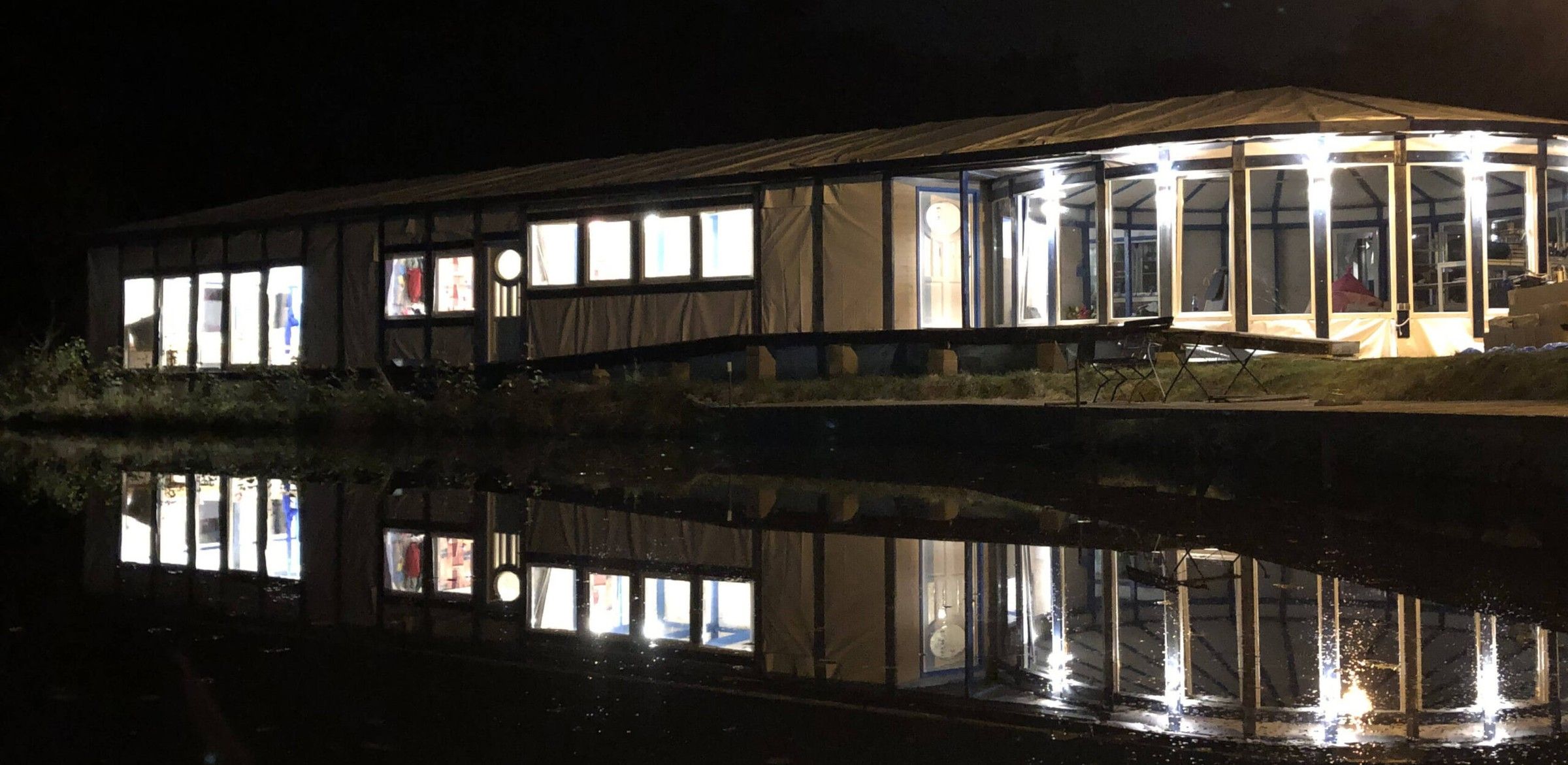Jurty Leśnego Montessori nocą, światła odbijają się w stawie