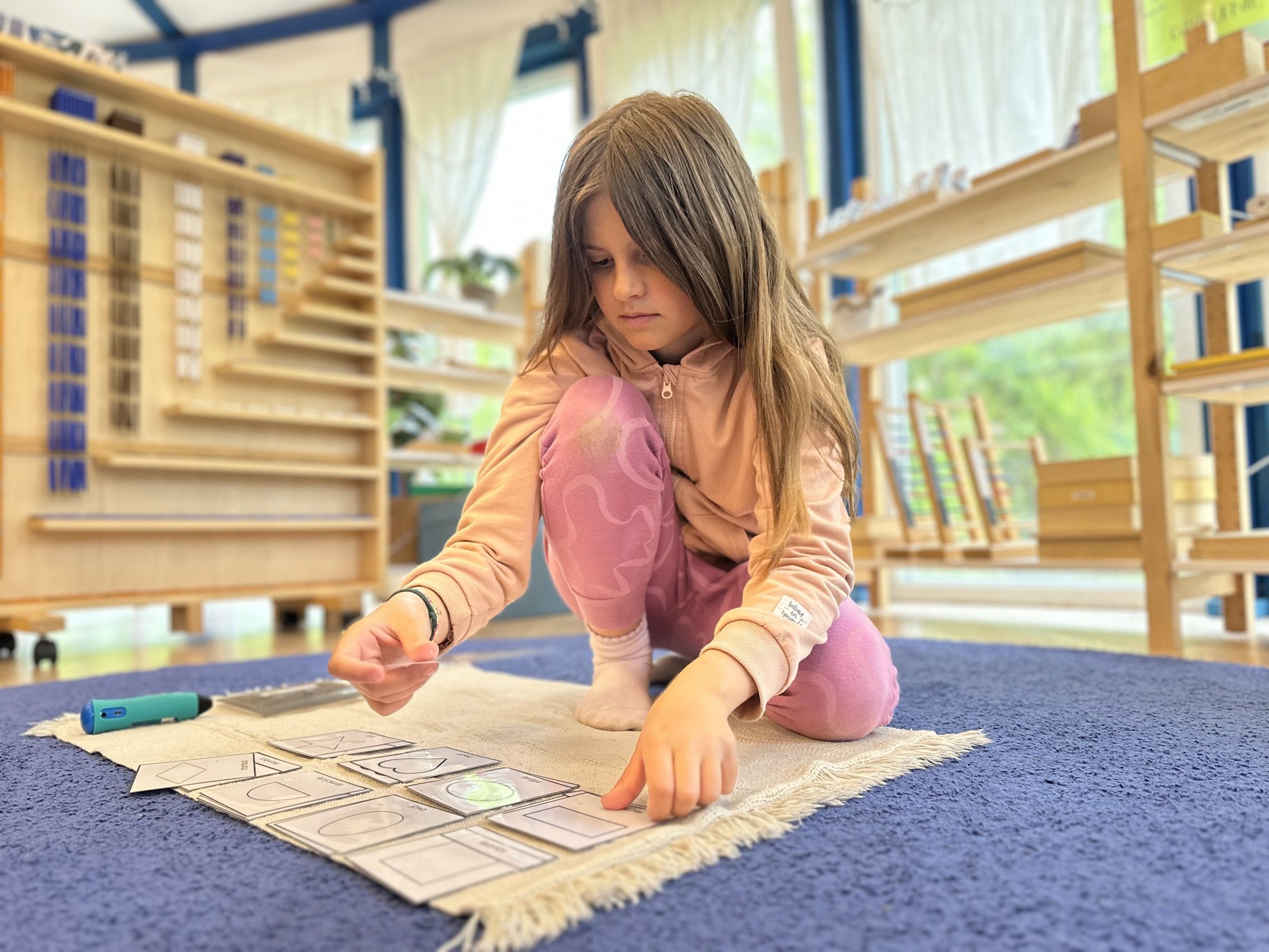 Uczennica pracuje z pomocą Montessori na dywaniku w jurcie